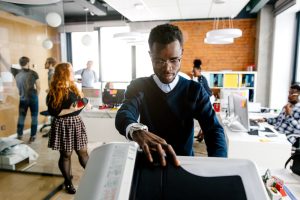 Employee using a multifunction office printer in a modern workplace.